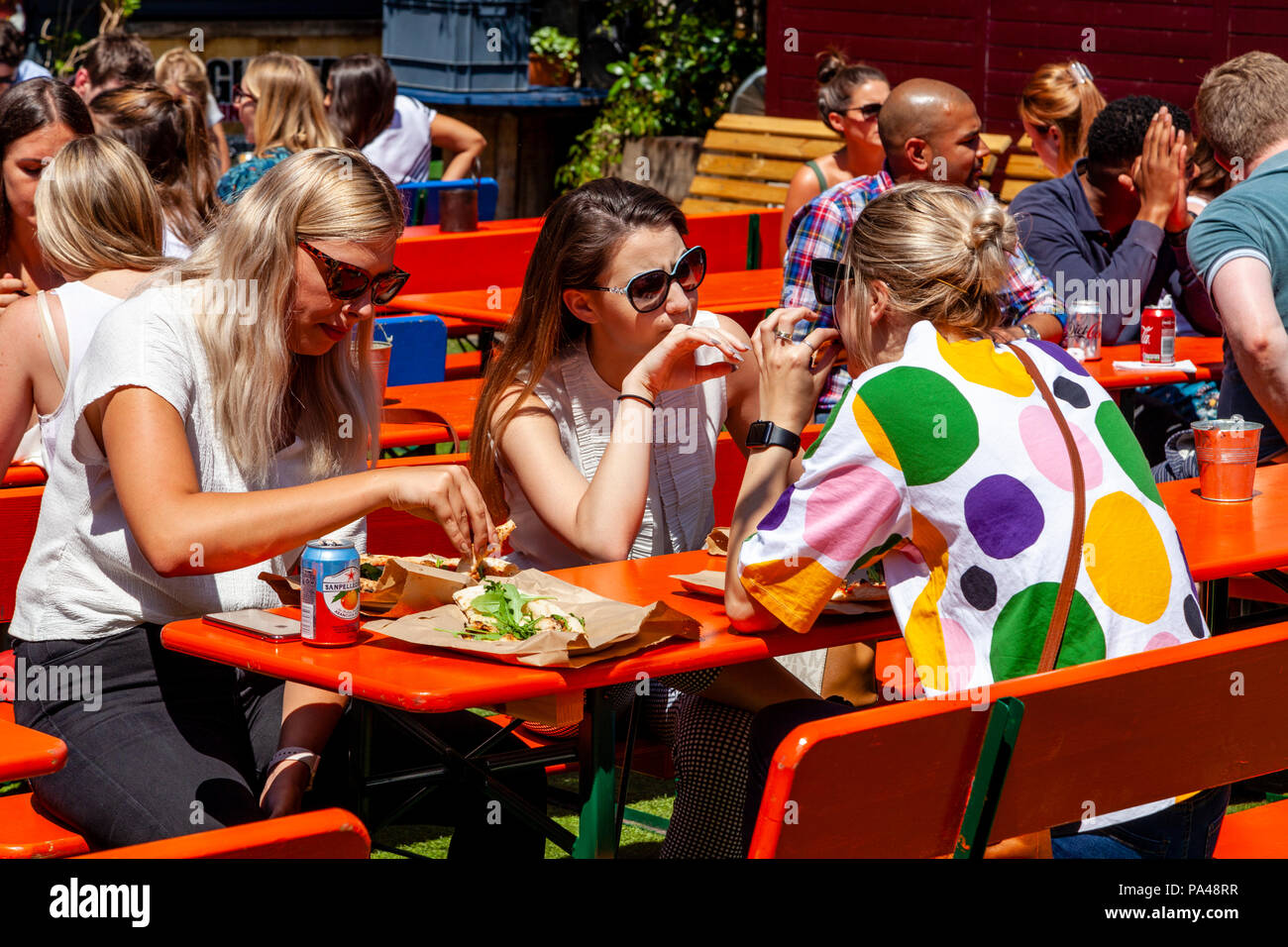 Un gruppo di giovani donne godendo un Lunchbreak in ferro piatto quadrato, Southwark Street, Londra, Inghilterra Foto Stock