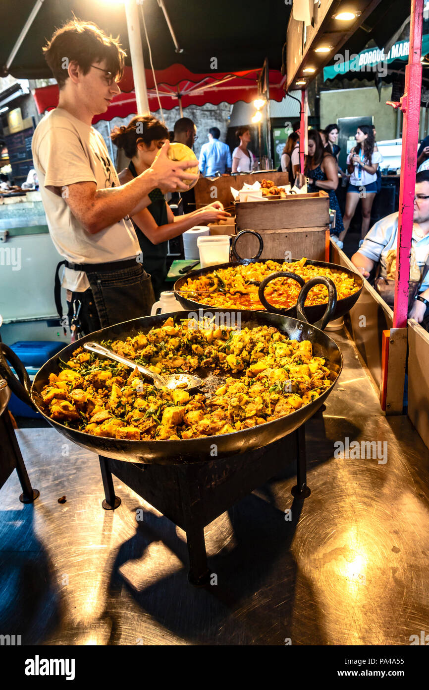 Due lavoratori presso il gujarati Rasoi Indian Street Food in stallo la preparazione per il servizio al famoso e storico Mercato di Borough, Southwark, Londra, Regno Unito Foto Stock