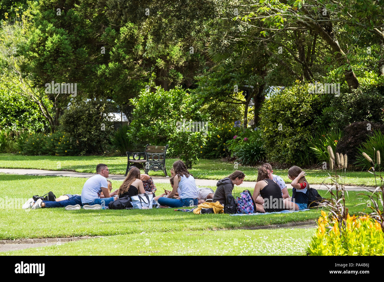 Un gruppo di giovani adulti rilassante in ombra in un parco a Newquay in Cornovaglia. Foto Stock