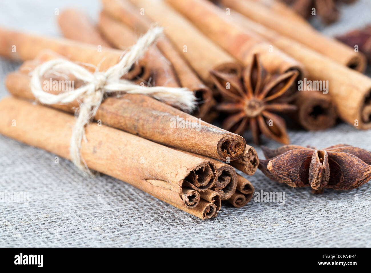 Fragranti bastoncini di cannella e anice a forma di stella, giacente insieme su un materiale costituito da filati di lino, un primo piano del piacevole spezie usate Foto Stock