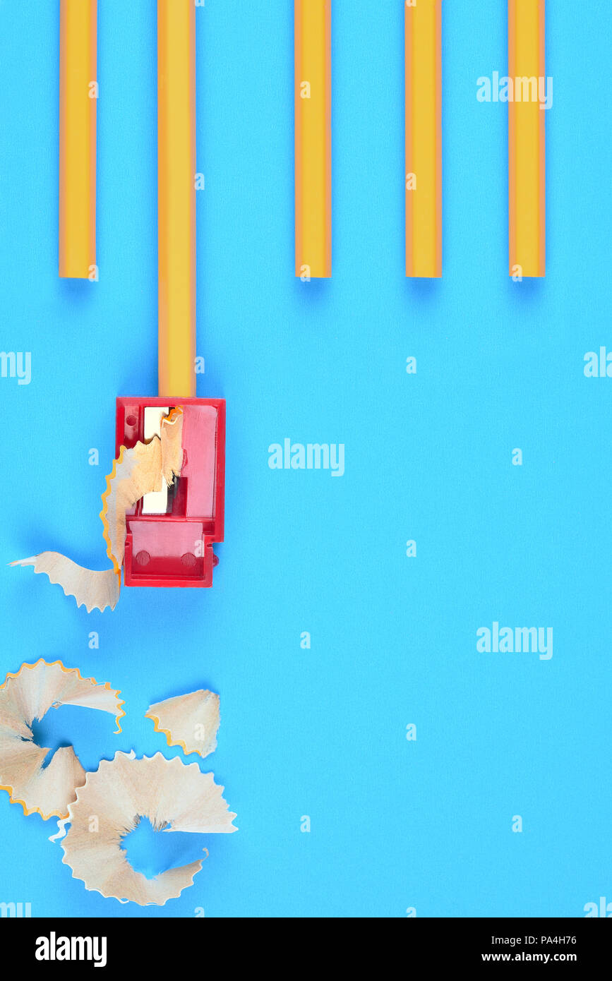 Si torna a scuola il concetto: Unsharpened matite di colore giallo con un temperino e trucioli, su uno sfondo blu. Copia dello spazio sul lato inferiore destro. Foto Stock