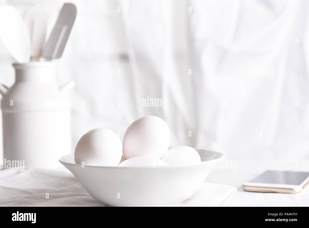 Tasto alto uovo ancora in vita: uova fresche in un bianco ciotola di fronte a una finestra con tende bianche. Orientamento orizzontale. Foto Stock