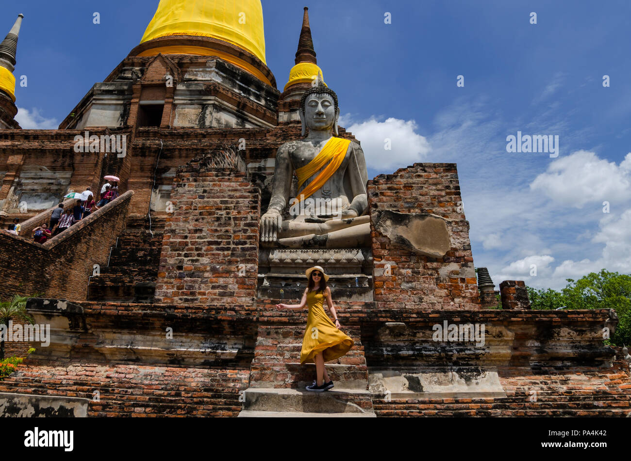 Ritratto di bella ragazza asiatica in abiti lunghi in posa davanti a un grande Buddha a Wat Yai Chai Mongkol. Il Wat è situato nei pressi di Ayutthaya. Foto Stock