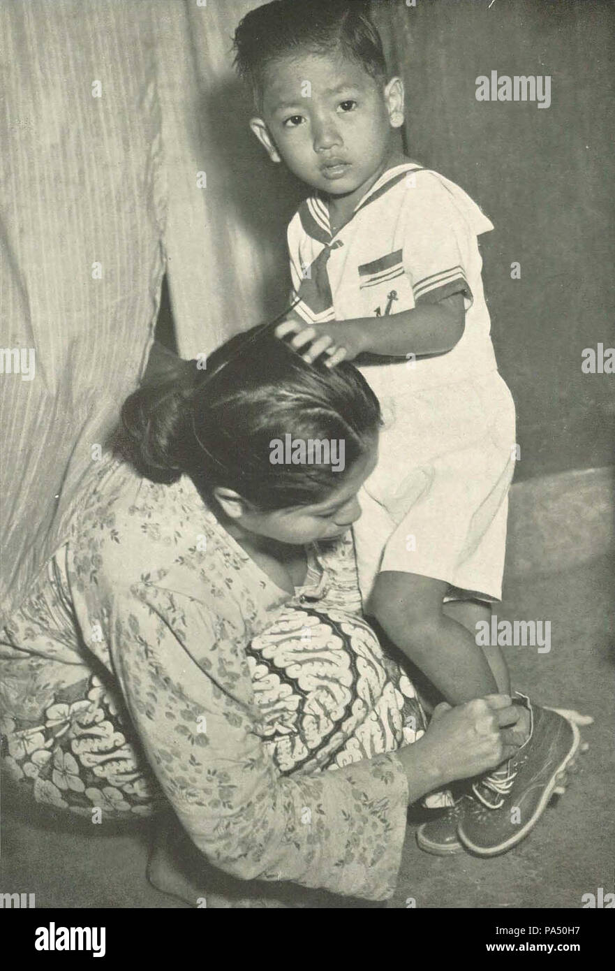 332 Donna vestire il figlio per il primo giorno di scuola, Wanita di Indonesia p43 (Ministero delle informazioni) Foto Stock