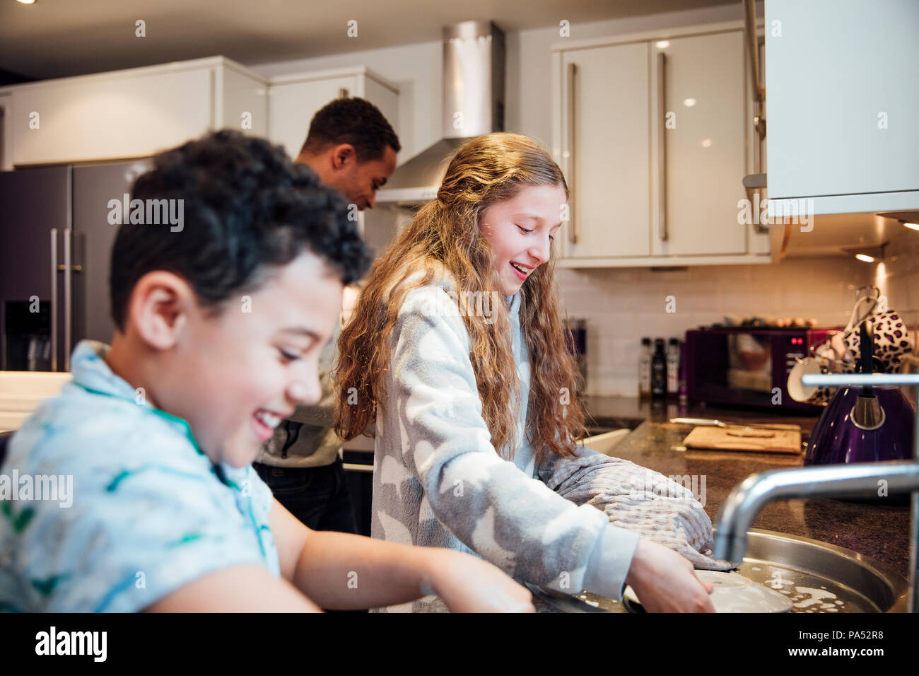 Bambina e suo fratello più giovane stanno facendo i piatti dopo la colazione a casa. Foto Stock