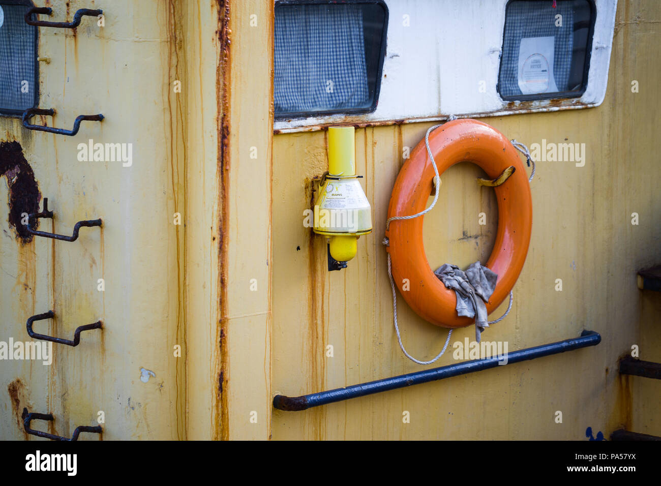 Vecchio giallo arrugginito barca da pesca, con orange anello di vita Foto Stock