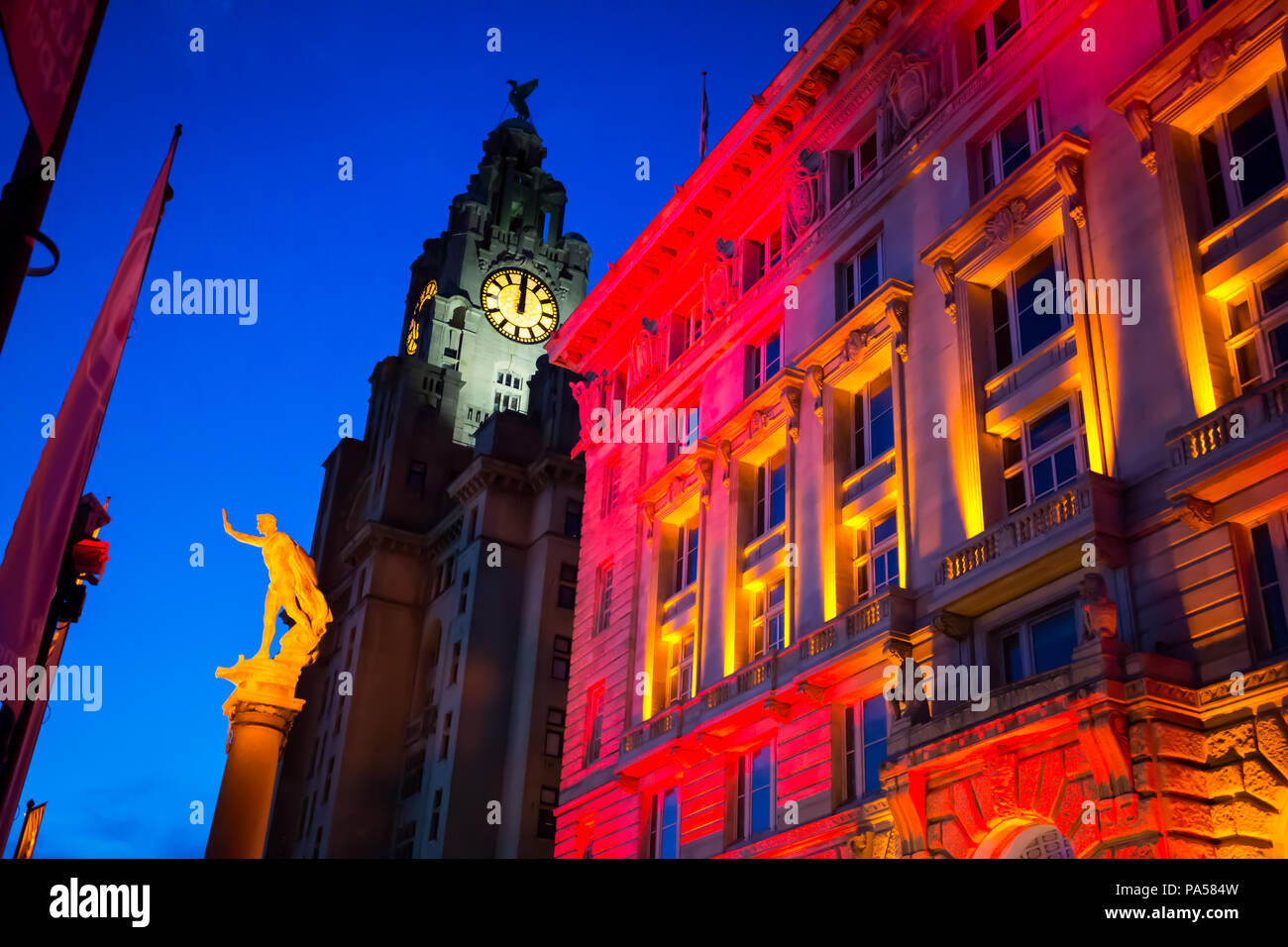 Notte Tempo shot del porto di Liverpool Building illuminato in rosso e luci di colore arancione, con il Royal Liver Building in background Foto Stock