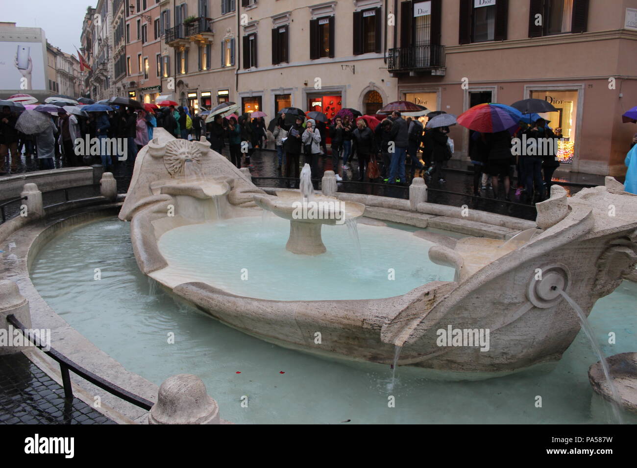 Un sacco di turisti camminare intorno alla piscina che è quello che si trova nei pressi di piazza di spagna sotto piovosa giornata cupa. Foto Stock