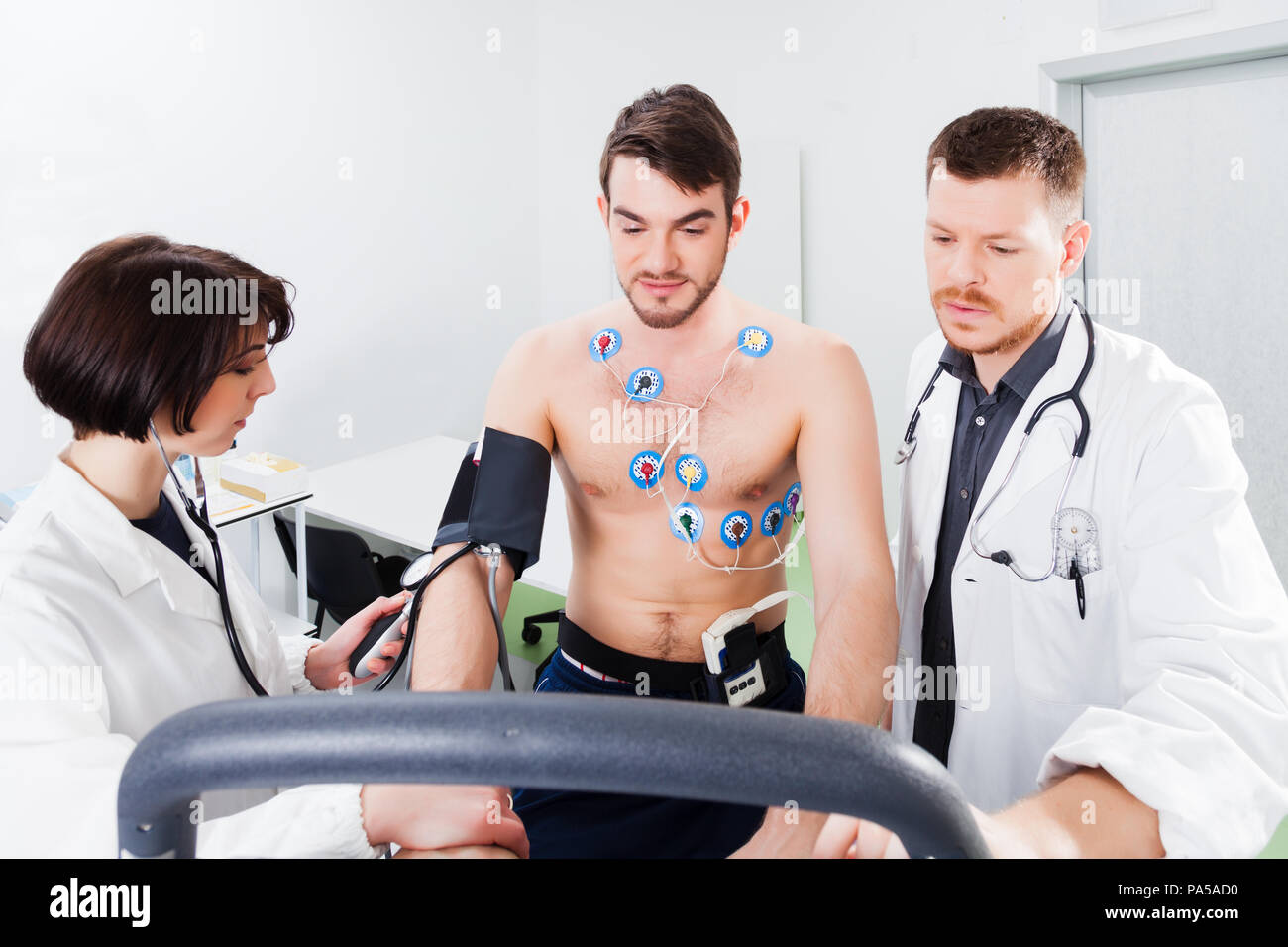 Atleta fa un stress cardiaco test in uno studio medico, monitorati dal medico e infermiere Foto Stock