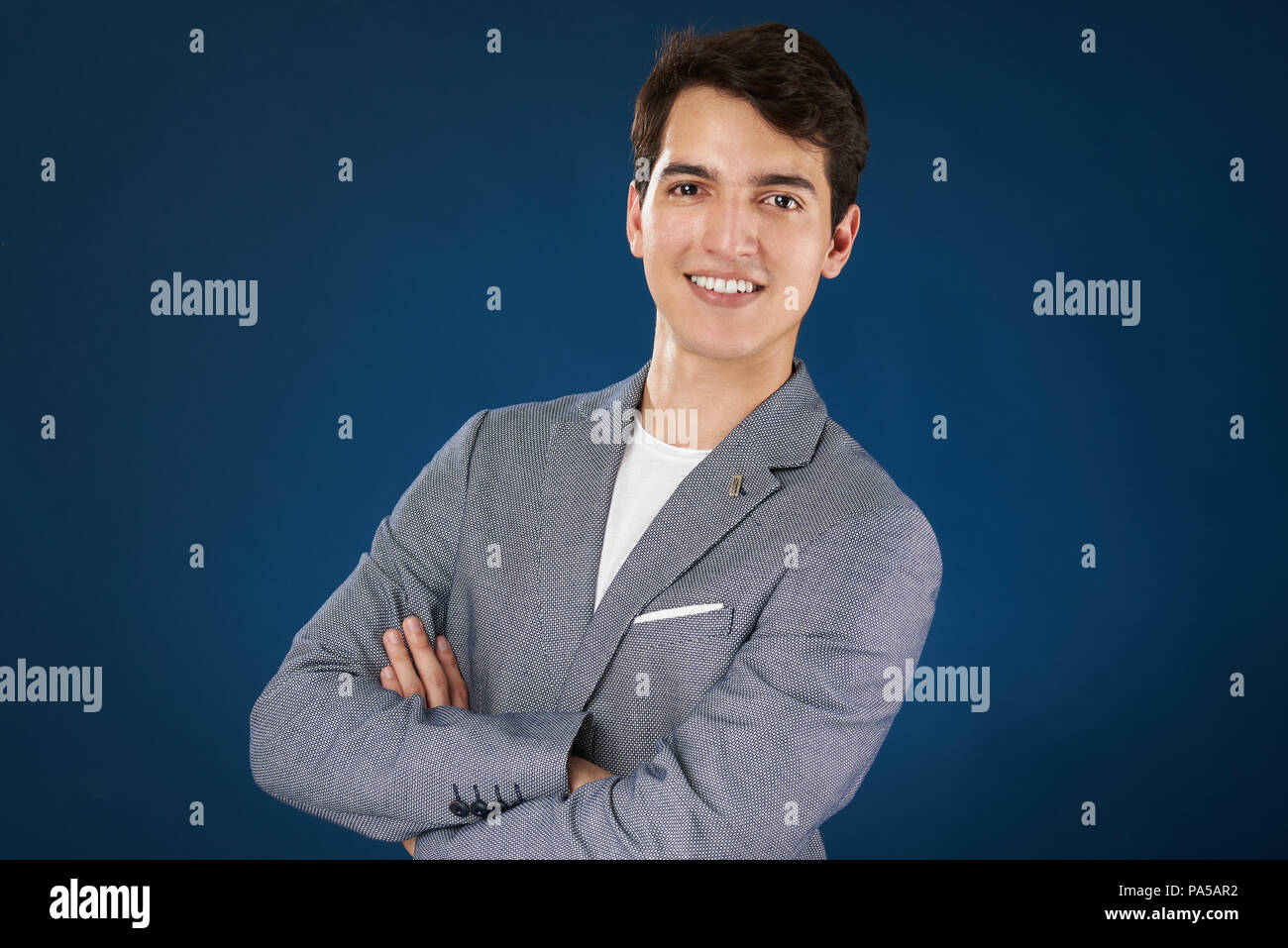 Sorridente uomo latino con bracci incrociati isolato su sfondo blu Foto Stock