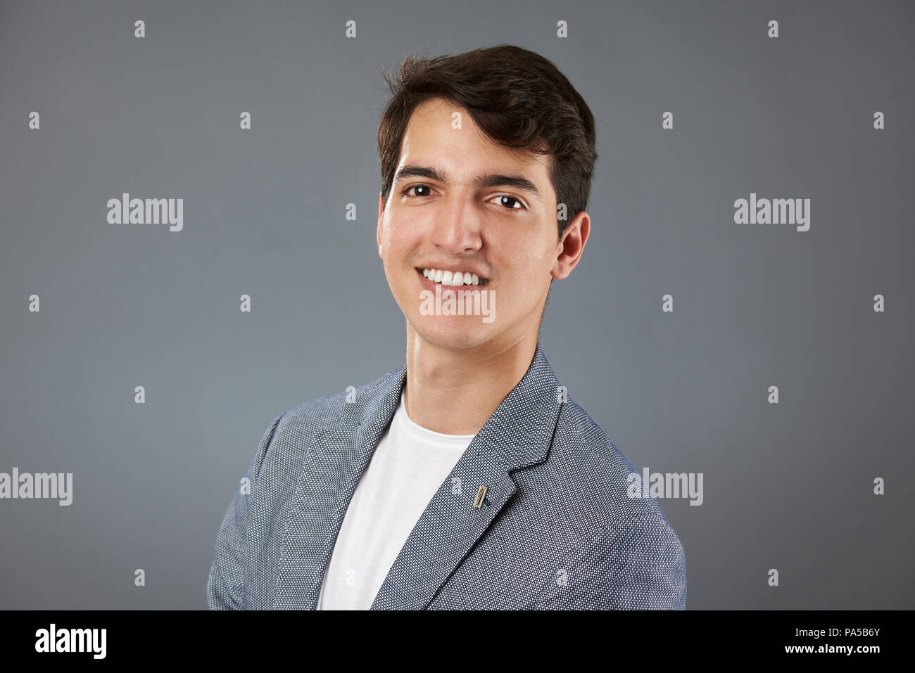 Sorridente con denti latino giovane uomo isolato su sfondo grigio Foto Stock