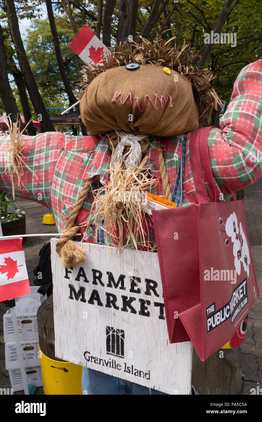 Ripiene di fieno spaventapasseri adornata con piccole bandiere canadesi flannel shirt e Granville Island Farmers Market segno. Foto Stock