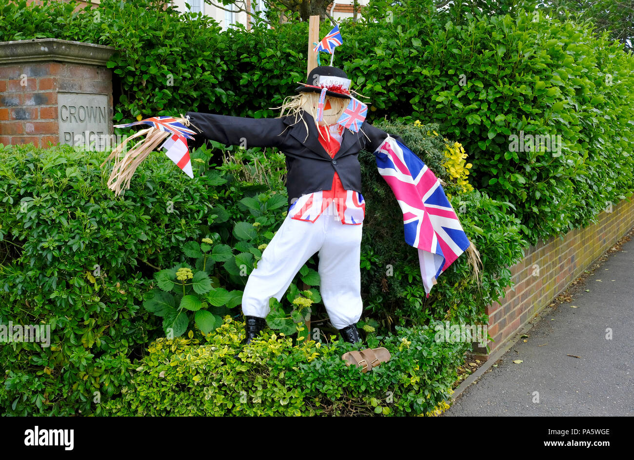 Maschio di spaventapasseri in giardino vestito come John Bull in dark giacca e pantaloni bianchi e azienda europea di bandiere e di Inghilterra bandiera Foto Stock