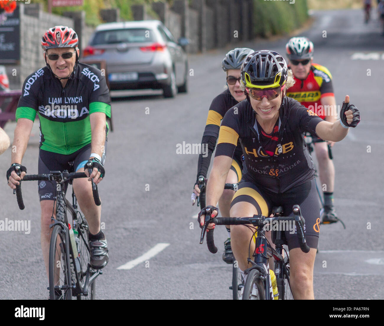 Gruppo misto dei ciclisti, in sella attraverso un villaggio in West Cork, Irlanda. Foto Stock