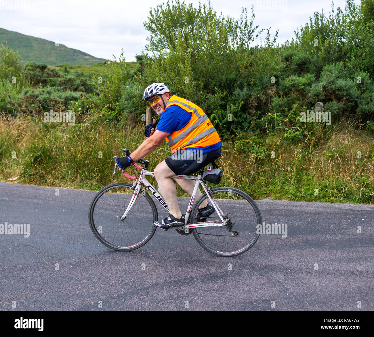 Ciclista godendo di una corsa in bicicletta attraverso strade di campagna del west cork, Irlanda. Foto Stock