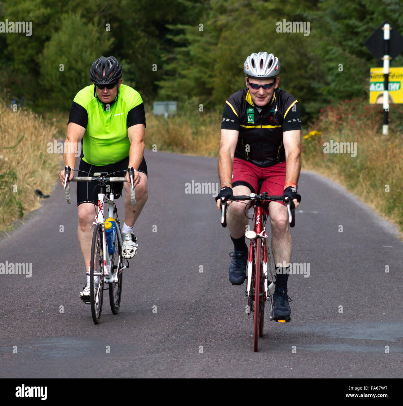 Ciclista godendo di una corsa in bicicletta attraverso strade di campagna del west cork, Irlanda. Foto Stock