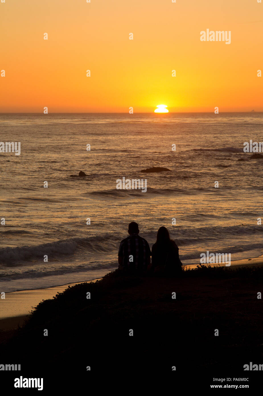 Due persone a guardare il tramonto sull'Oceano Pacifico Foto Stock