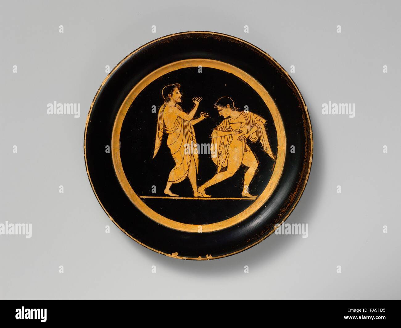 Piastra di terracotta. Cultura: greco, soffitta. Dimensioni: diam.: 7 1/2 in. (19,1 cm). Data: ca. 510 A.C. In tondo, due buontemponi, una riproduzione del doppio flauto, altri tenendo un skyphos (deep bicchiere). Museo: Metropolitan Museum of Art di New York, Stati Uniti d'America. Foto Stock