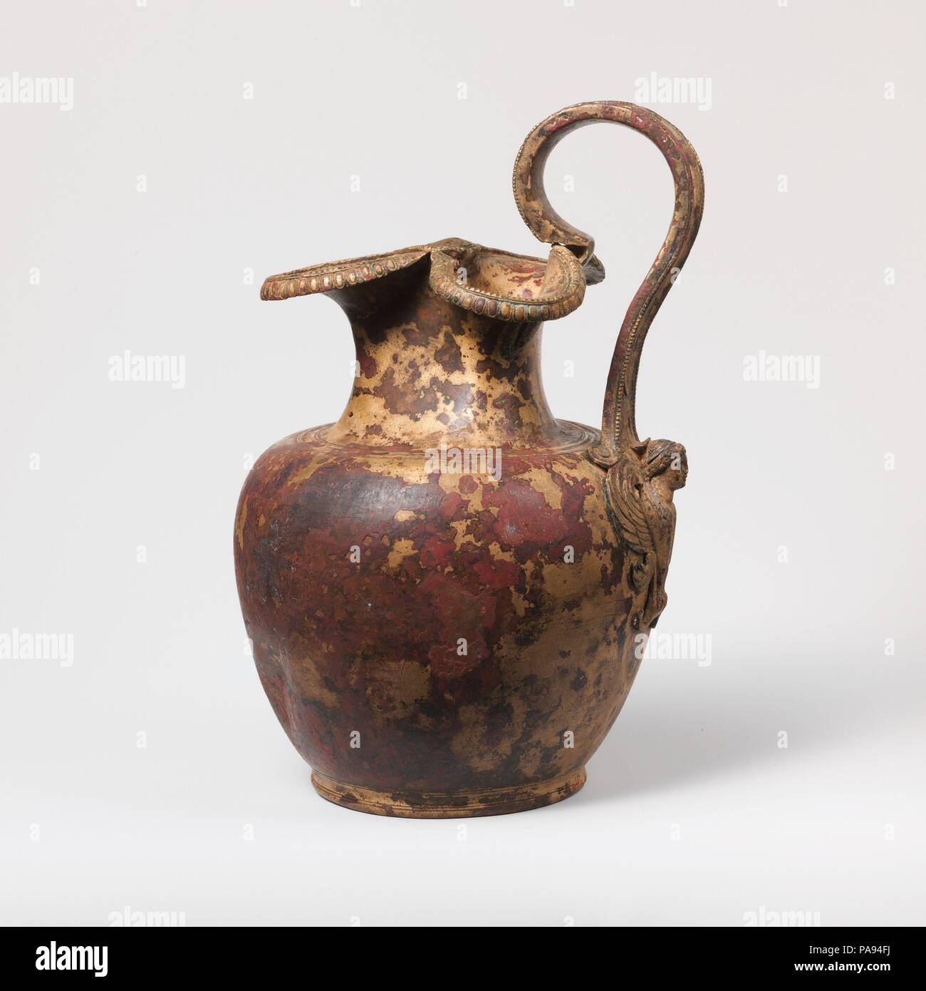 Oinochoe in bronzo (caraffa). Cultura: greco. Dimensioni: H.: 8 15/16 in. (22,7 cm). Data: ca. 460 A.C. L'attacco del manico è in forma di una sirena frontale. La funzione di un attacco del manico è quello di fissare la base della maniglia saldamente al corpo del vaso; una ampia superficie fornisce un legame più forte. Da un mero punto di vista meccanico, la sirena con le sue ali estesa soddisfa lo scopo in modo efficace. Indossa un filetto di argento. Museo: Metropolitan Museum of Art di New York, Stati Uniti d'America. Foto Stock