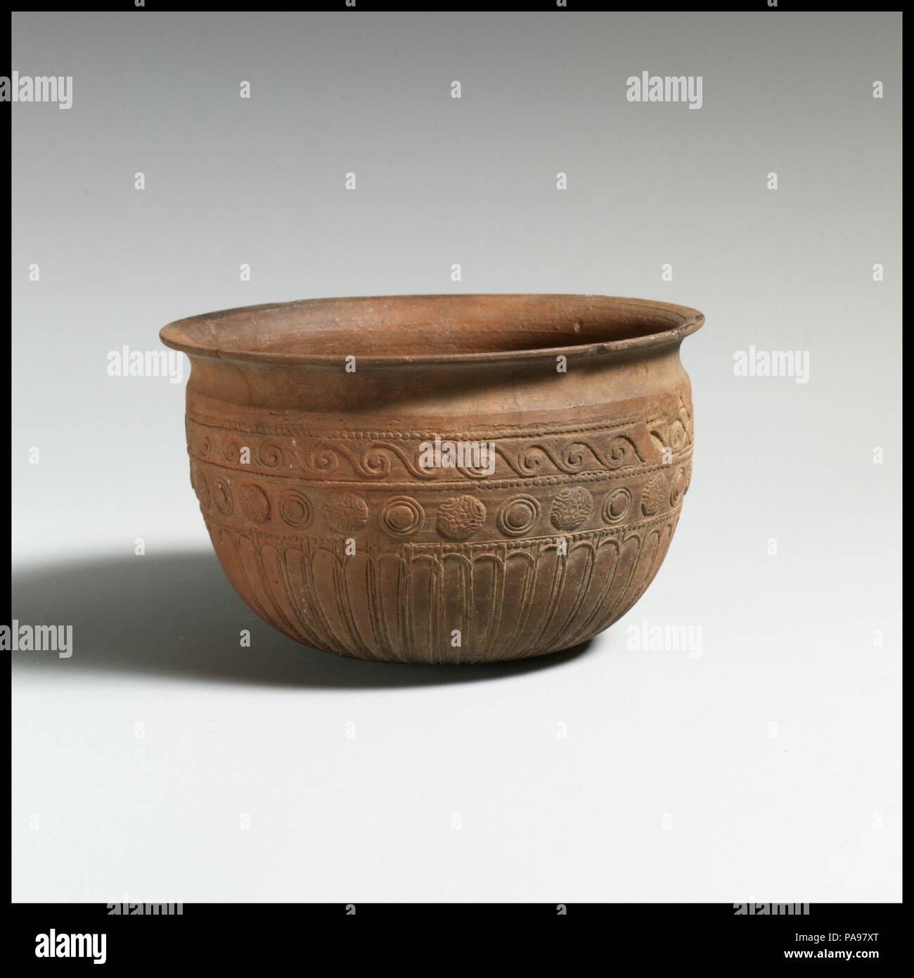 In Terracotta ciotola Megarian. Cultura: Romano. Dimensioni: h. 2 5/8 in. (6.7 cm); d. 4 3/8 in. (11,1 cm). Data: ca. 150-100 A.C. I motivi in rilievo la decorazione di questo recipiente si trovano spesso sulla merce prodotta da alcuni dei più ben attestata creatori di pianura emisferica sparato in ceramica. Protezioni, per esempio, erano un motivo particolarmente favorito da C. Popilius, come si vede sul recipiente in questo caso che reca la sua firma (96.18.79). L'onda ornamento e zona di petali a lungo su questa ciotola però trovare parallels sulle navi firmato da Lapius, un contemporaneo di Popilius. Questo recipiente unsigned fu probabilmente realizzato da un Foto Stock
