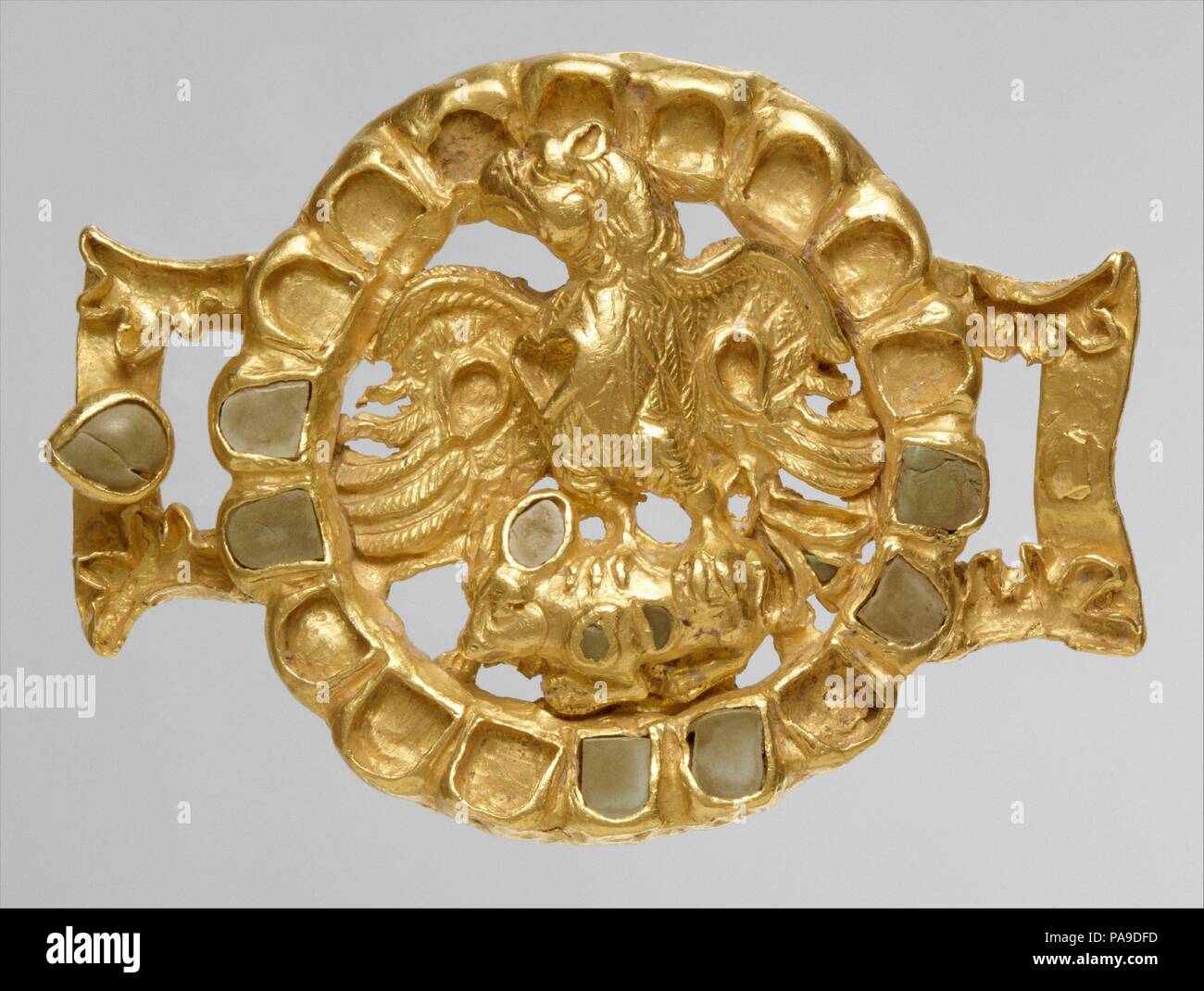 Chiusura con un aquila e la sua preda. Cultura: Parthian. Dimensioni: h cm 6, W. 8.4 cm. Data: ca. A.D. 1a-2a secolo. Questo solido oro ornamento è in forma di un roundel con due elementi sporgenti che hanno delle asole per il fissaggio di una cinghia. Il cerchio della roundel, costituito da diciotto miniatura celle di forma per intarsio turchese nel modo di alcuni Sarmatian roundels, telai di openwork la figura di un aquila in altorilievo. Afferrare un piccolo, accovacciato animale nella sua talons ", la voliera degli uccelli in vista in tre quarti, rivolto verso destra con il suo petto esteso e il resto del suo corpo rientranti nella Foto Stock