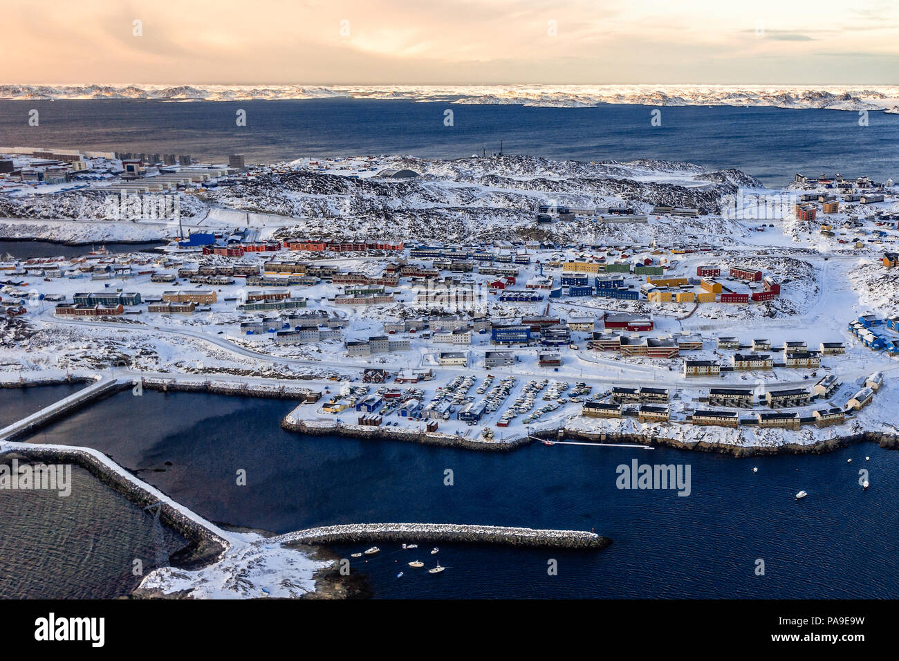 Antenna vista al tramonto di strade con coloratissime case inuit e vivono isolati in pieno di neve con fjord in background, Nuuk Groenlandia Foto Stock