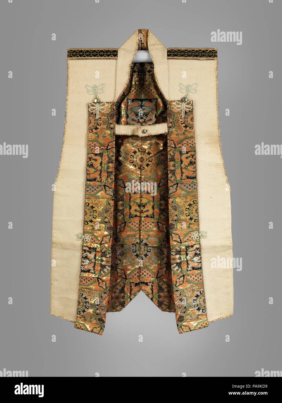 Surcoat (Jinbaori). Cultura: giapponese. Dimensioni: H. 42 1/8 in. (107 cm); W. 26 3/8 in. (67 cm). Data: ca. 1866. La Famiglia Tokugawa mon (emblema araldico), costituito da un cerchio che racchiude tre holly foglie, è applicato al centro della schiena in spesse in velluto nero. La fodera e il revers sono coperti con un lussuoso broccato di seta dotato di una configurazione di ripetizione di quadrate e rotonde cartouches riempito di fiori e di coppie di draghi e fenici. Secondo una etichetta fissata ad esso, questo surcoat apparteneva a Yoshinobu Tokugawa (1837-1913), ultimo shogun (righello militare) del Giappone ( Foto Stock