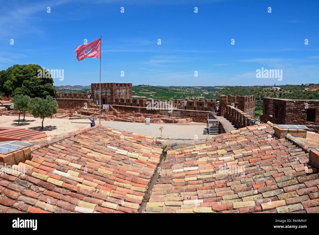 Vista le rovine e i giardini del castello medievale con merli e torri a posteriori con i turisti che si godono la impostazione, Silves, Portogallo, Foto Stock