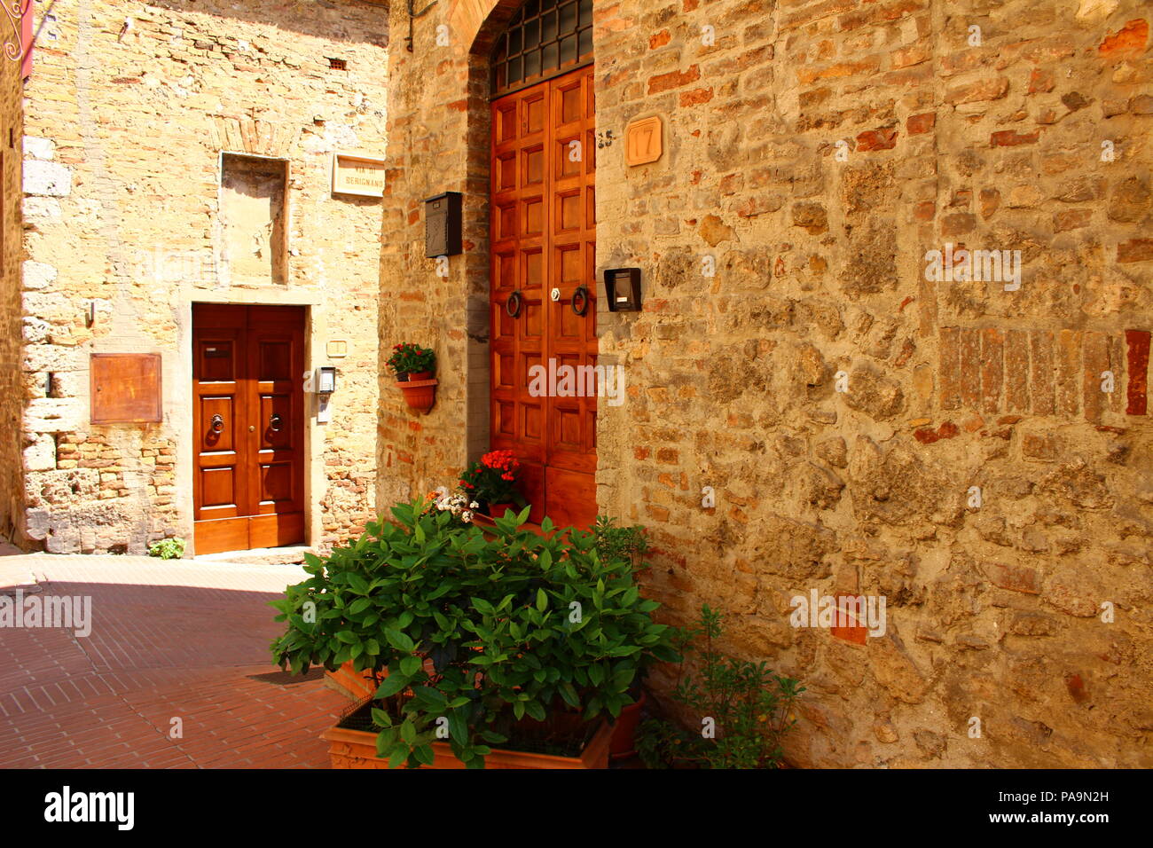 Fiori nella parte anteriore di una porta in una delle strette strade di San Gemignano, Italia Foto Stock