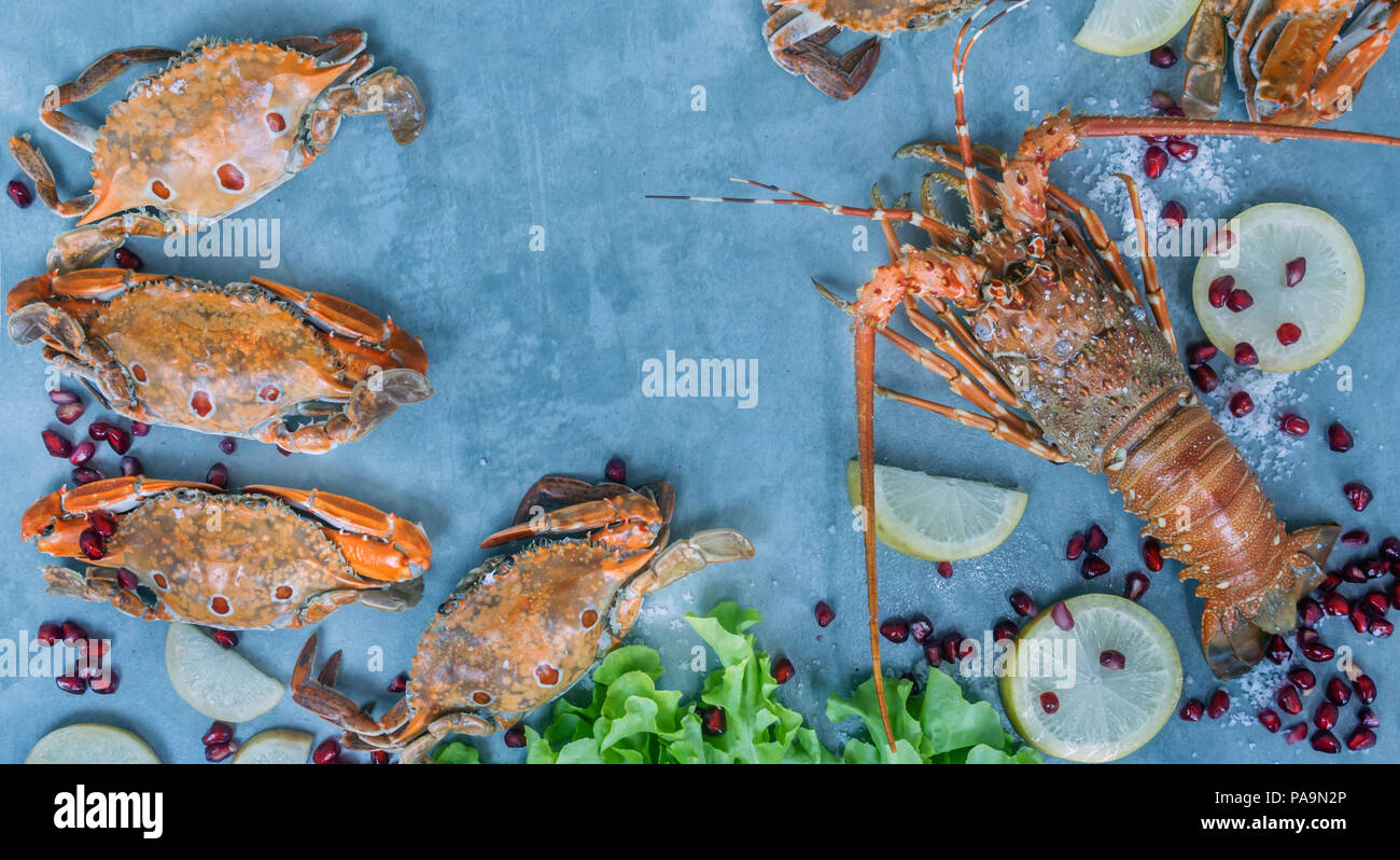 Telaio di alimentare con i crostacei . Aragosta, granchio, limone e melograno sullo sfondo Foto Stock