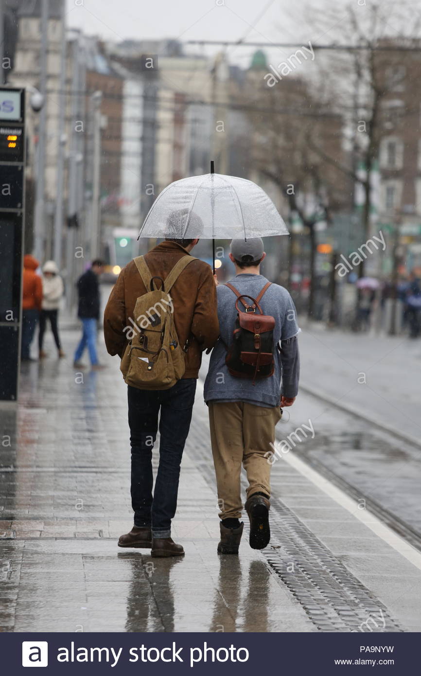 La gente camminare sotto la copertura di un ombrellone in un giorno di pioggia a Dublino, Irlanda. Foto Stock