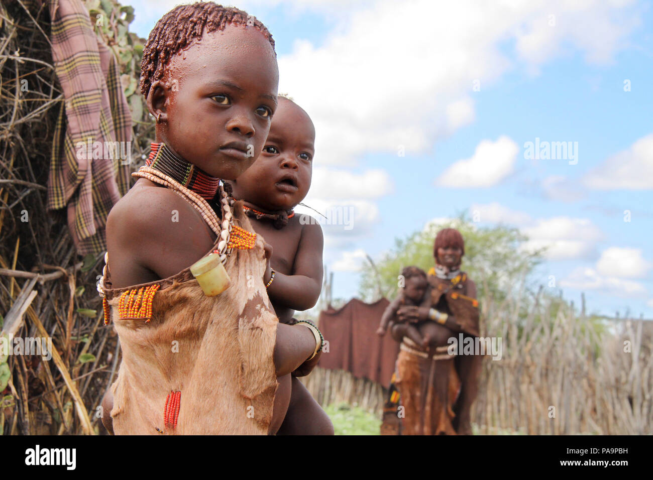 Una ragazza Hamer porta il suo fratello durante il Bull Jumping cerimonia (Ukuli rituale) da Hamer Hamar tribù, Etiopia Foto Stock