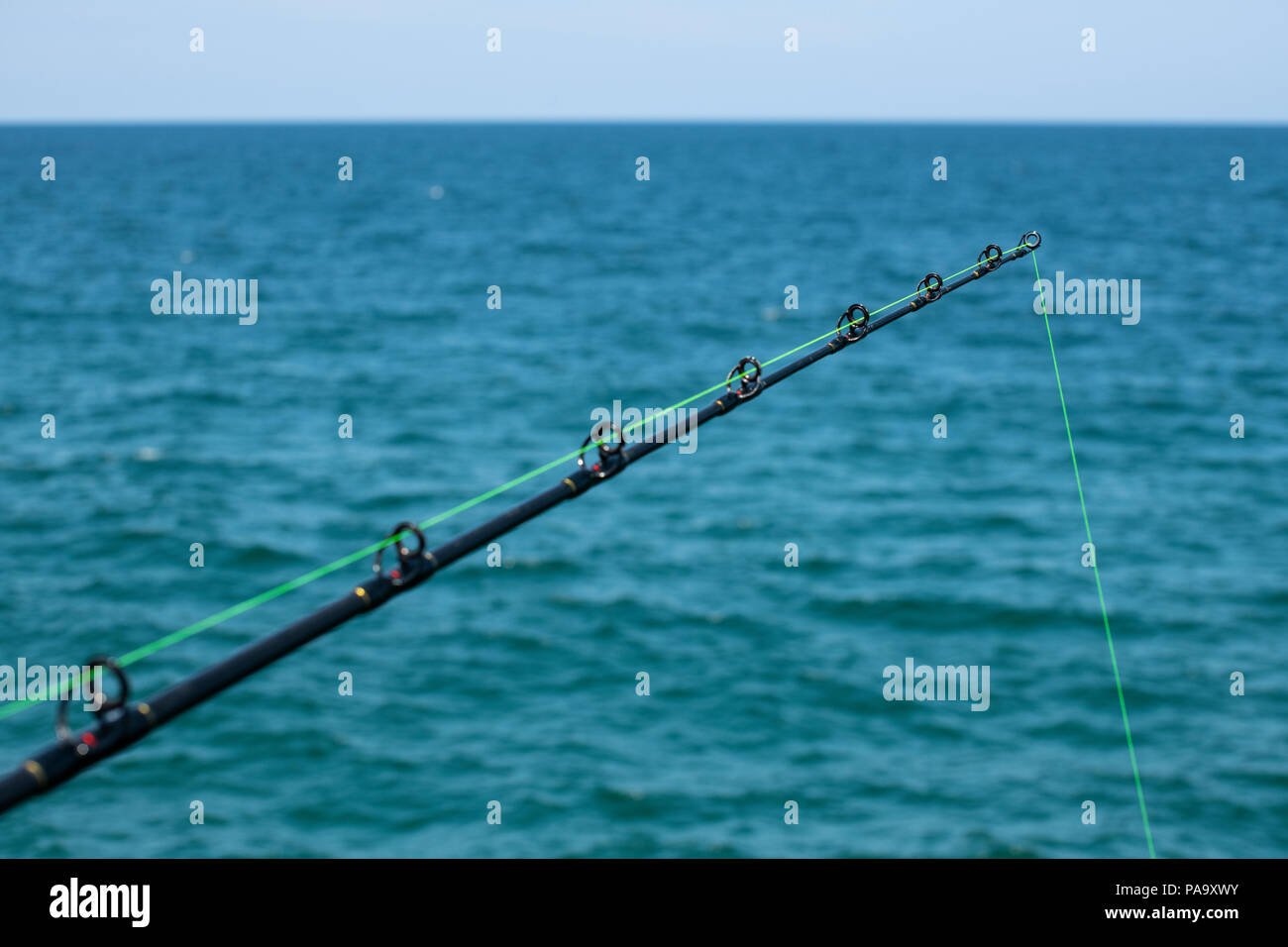 Una canna da pesca contro il blu oceano Foto Stock