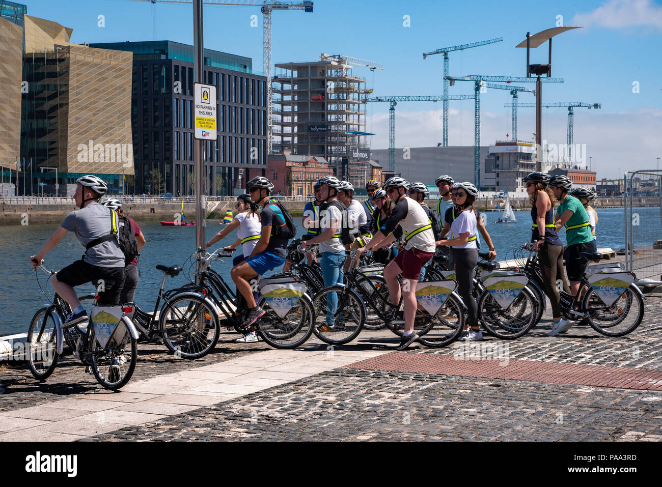 Un gruppo di turisti in bicicletta è guardare oltre il fiume Liffey a Dublino, Irlanda. Foto Stock