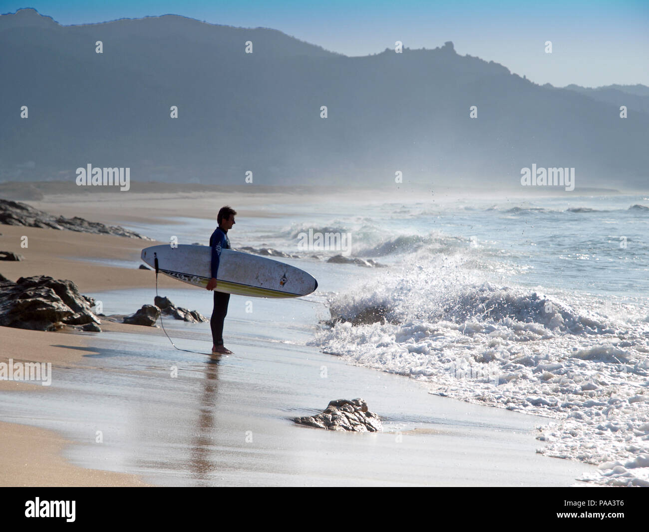Un surfista sulla spiaggia sulla costa della Galizia, Spagna settentrionale Foto Stock
