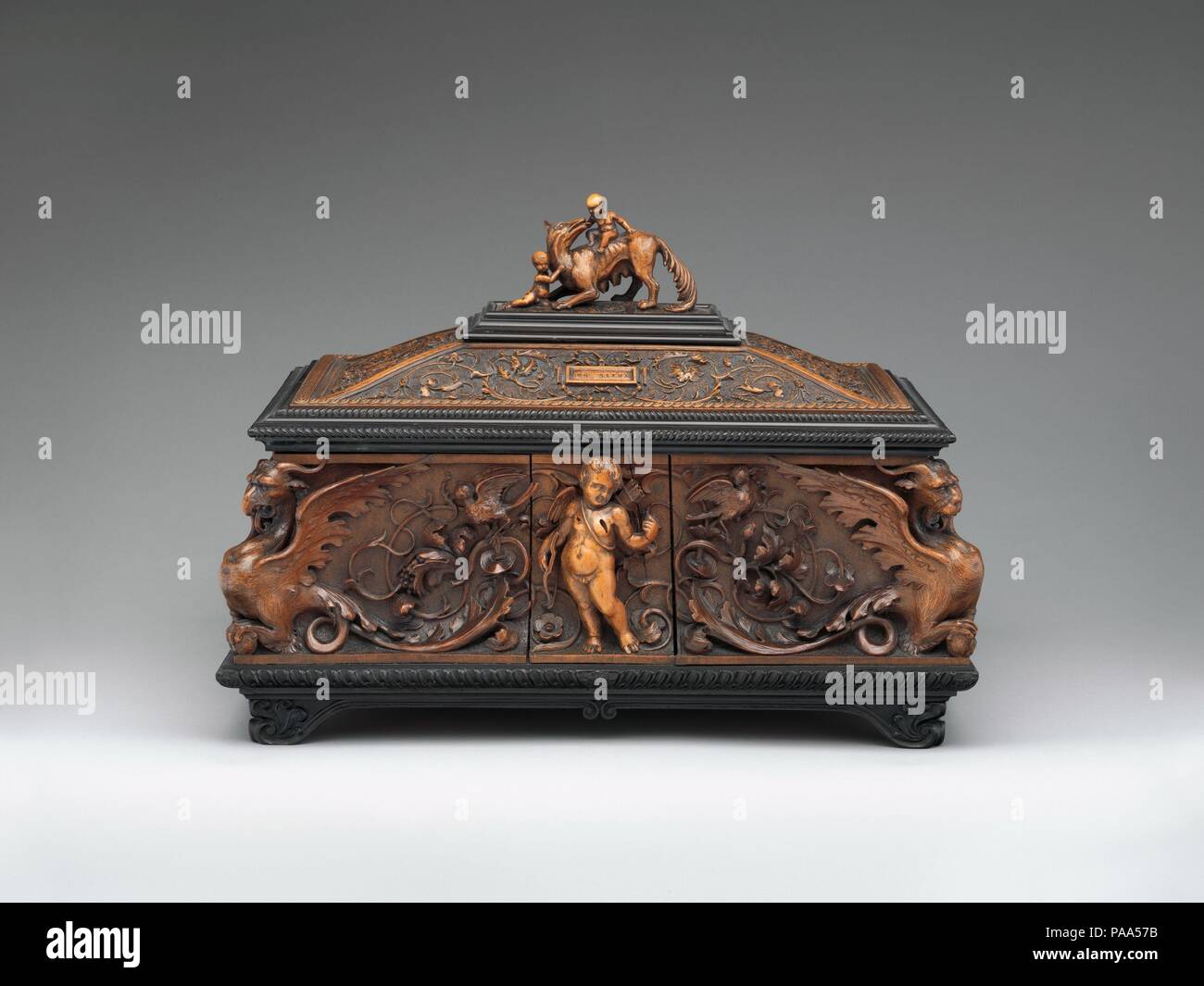 Scrigno di gioielli. La cultura italiana, Siena. Dimensioni: 11 x 15 x 10-1/4 in. (27,9 x 38,1 x 26,0 cm). Autore: Pietro Giusti (Italiano, 1822-1878). Data: 1857. Pietro Giusti, uno di maggior successo del diciannovesimo secolo i progettisti e gli scultori in Toscana, era conosciuto per la sua riccamente intagliati e telai mobili in sedicesimo secolo stili. Qui, Giusti possono essere stati ispirati dal lavoro dell'artista rinascimentale Antonio Barili (1453-1516); Guisti era probabilmente familiarità con barili di cassone sormontato dalla lupa con Romolo e Remo e con il mitico mostri in corrispondenza dei quattro angoli del Museo Foto Stock