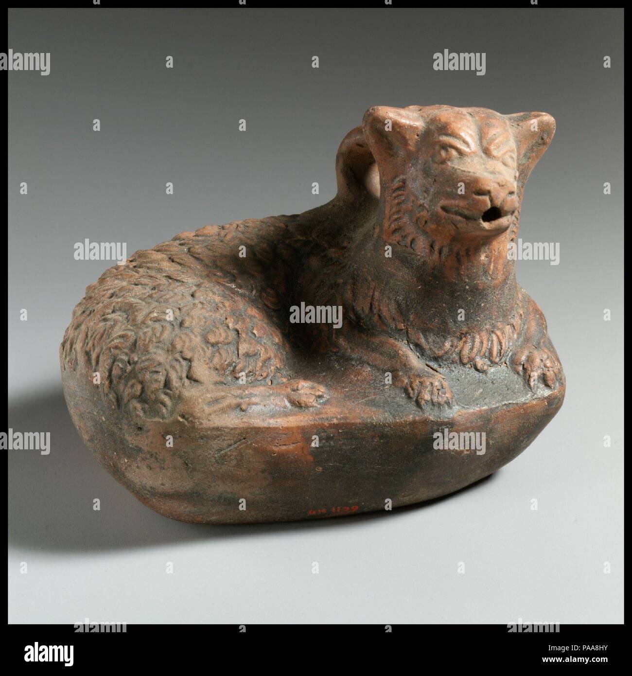 Askos in terracotta sotto forma di un cane. Cultura: greco. Dimensioni: h. 3 9/16 in. (9.1 cm); w. 4 7/16 in. (11,3 cm). Data: 2nd-1st secolo a.c. inscritto 'EUPLOUS' Questo askos sotto forma di un cane reclinabile è correlata alla Magenta Ware palloni visualizzati nelle vicinanze (06.1021.265, 07.286.131). La sua classificazione come un esempio di Magenta Ware in ceramica, tuttavia, è impedito dalla mancanza di qualsiasi traccia del profondo pigmento rosso che normalmente caratterizza la tecnica. Il nome riportato sulla base di askos è attestata nelle iscrizioni di Beozia in Grecia centrale e può forse il punto a Foto Stock