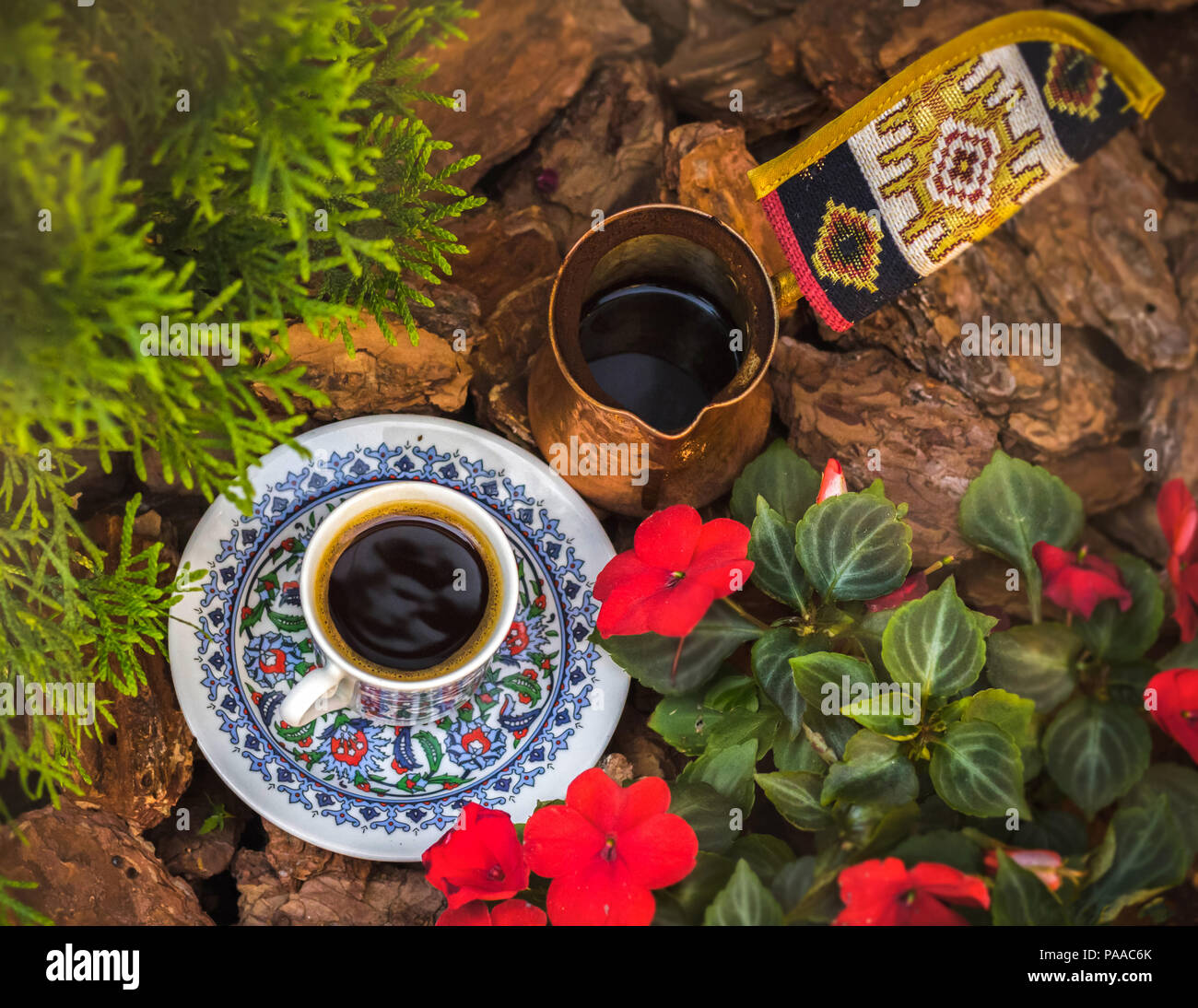Una tazza da caffè con piattino e jezva stand tra la corteccia, fiori e rami di cipresso. Vista superiore Foto Stock