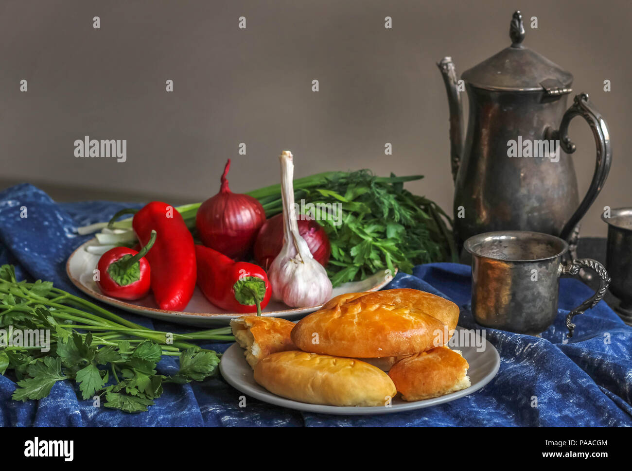 Polpette fatte in casa su una piastra bianca su uno sfondo di peperoni rossi e erbe aromatiche. Nelle vicinanze di un antico oriental brocca e una tazza di nichel-argento Foto Stock