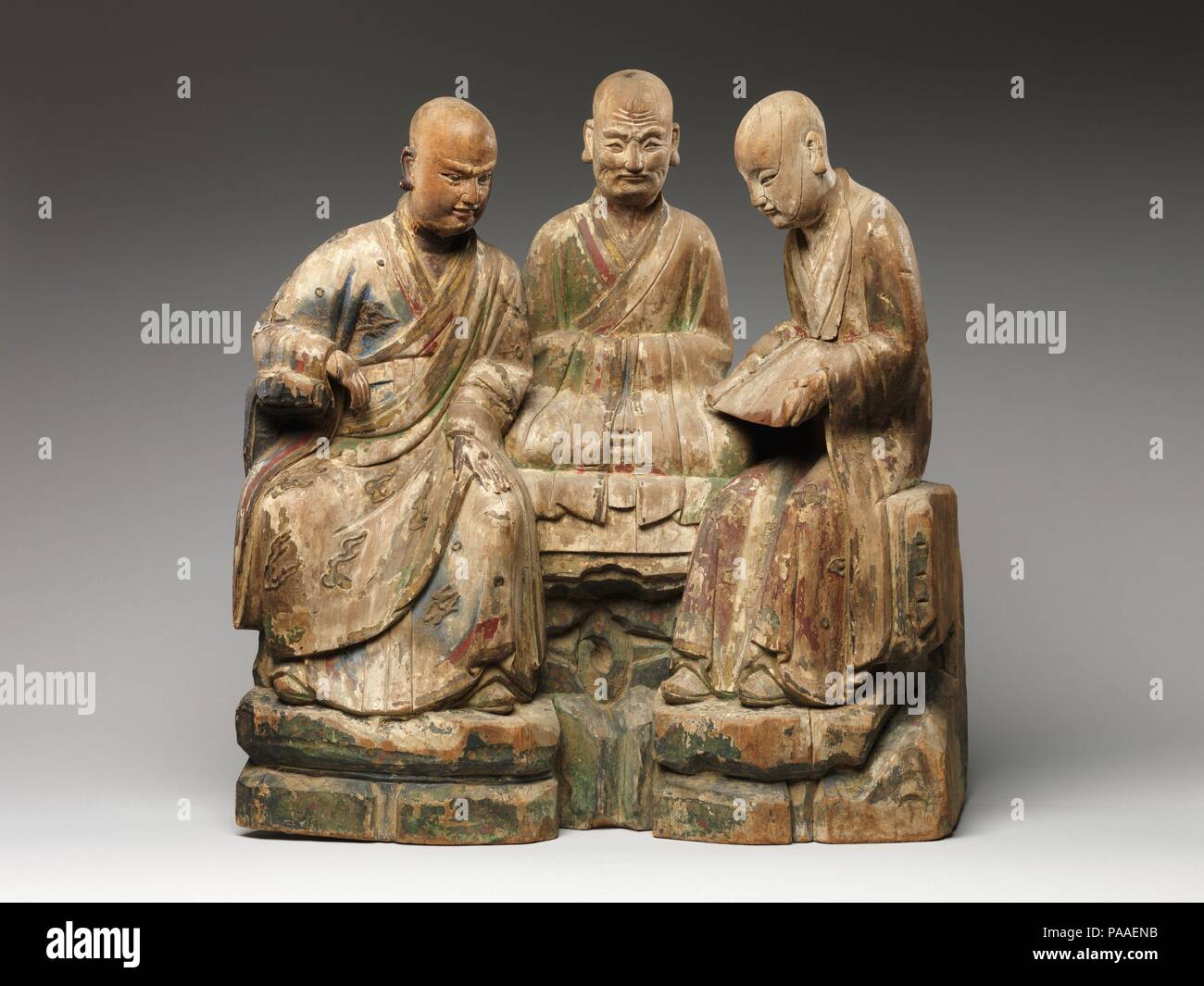 Tre Arhats (Luohans). Cultura: la Cina. Dimensioni: H. 22 1/4 in. (56,5 cm); W. 22 a. (55,9 cm); D. 7. (17,8 cm). Data: XVI-XVII secolo. Con il diffondersi di Chan (Zen) del Buddismo in Cina nel decimo secolo, Louhans, illuminati saggi buddista, erano spesso rappresentati come monaci di eseguire gli esercizi spirituali. Seduti sul sommariamente sbozzati rocce, questi tre louhans sono impegnati nello studio e nella meditazione. Le loro vesti erano originariamente colorati e dorati con un gesso di massa. Ricavato da un unico pezzo di legno, le tre figure sono state probabilmente parte di un assemblaggio di grandi dimensioni. Museo: Metropolitan Museum of Art di New Foto Stock