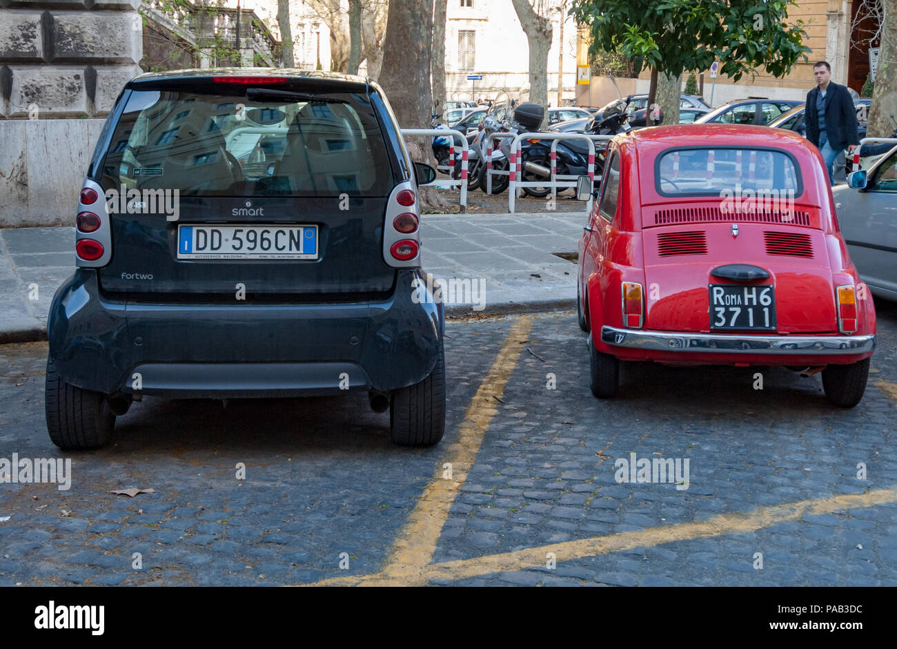 In che modo il nostro concetto di piccolo è cambiato nel corso di quarant'anni. Un originale Fiat Cinquecento accanto a una Smart fortwo auto in un lato di Roma Street. Foto Stock