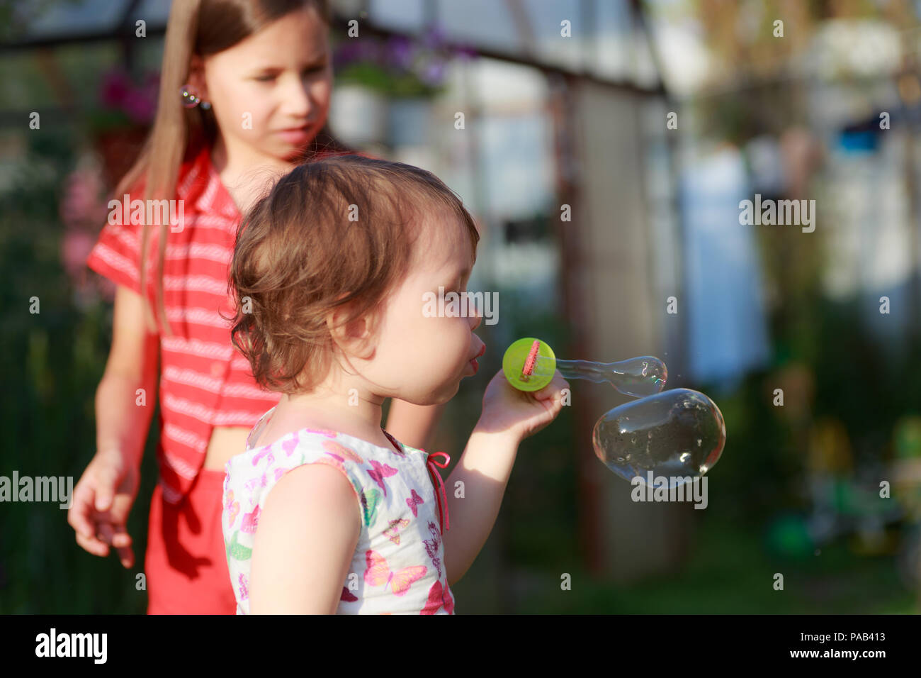 Carino bambina sta soffiando una bolle di sapone Foto Stock