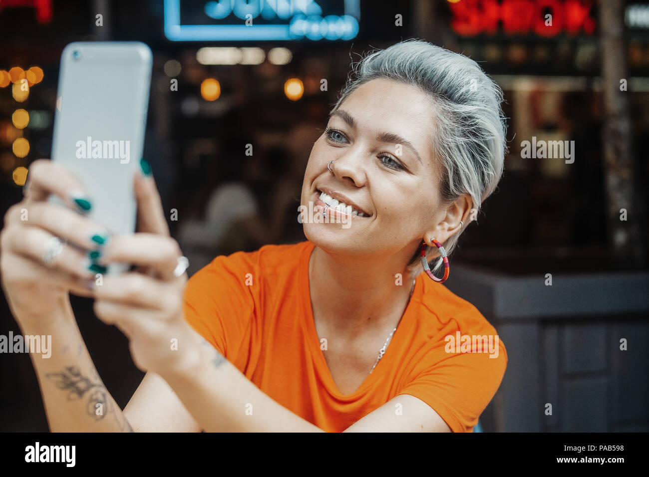 Close up attraente ragazza bionda in T-shirt rendendo selfie presso il cafe Foto Stock