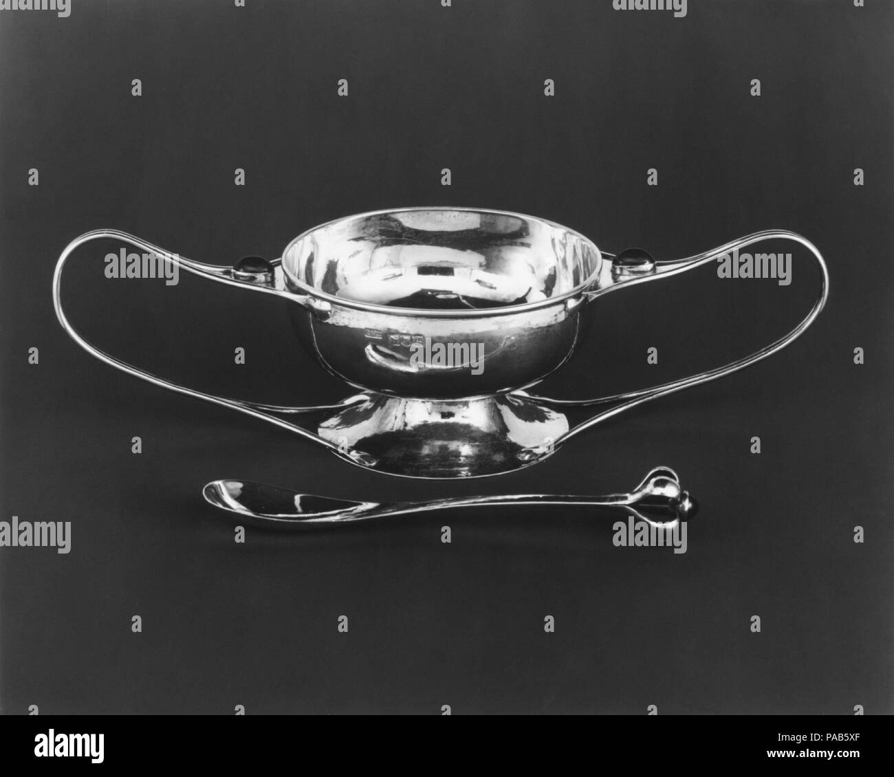 Porringer e cucchiaio. Progettista: Charles Robert Ashbee (British, Isleworth, Middlesex 1863-1942 Godden verde, Kent). Dimensioni: H. 2-13/16, W. 10-5/8, D. 4-1/4 in. (7,1 x 27,0 x 10,8 cm). Maker: Guild di artigianato (britannico). Data: 1902-4. Un influente designer di arti e mestieri di movimento in Gran Bretagna, Ashbee fondata la gilda di artigianato nel 1888 come una cooperativa di un autodidatta artigiani che hanno reso mobili, lamiera, marocchineria e gioielli. Ashbee fu il progettista predominante della gilda, sviluppare uno stile elegante che si è rotto in modo significativo da tradizioni Vittoriano. È stato notevole Foto Stock