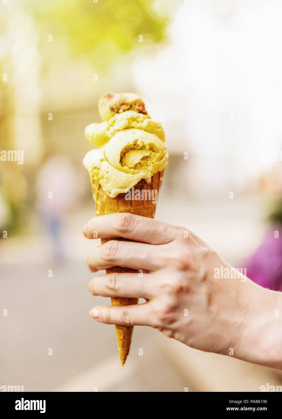 Femmina lato tenendo cono gelato contro sfondo sfocato Foto Stock