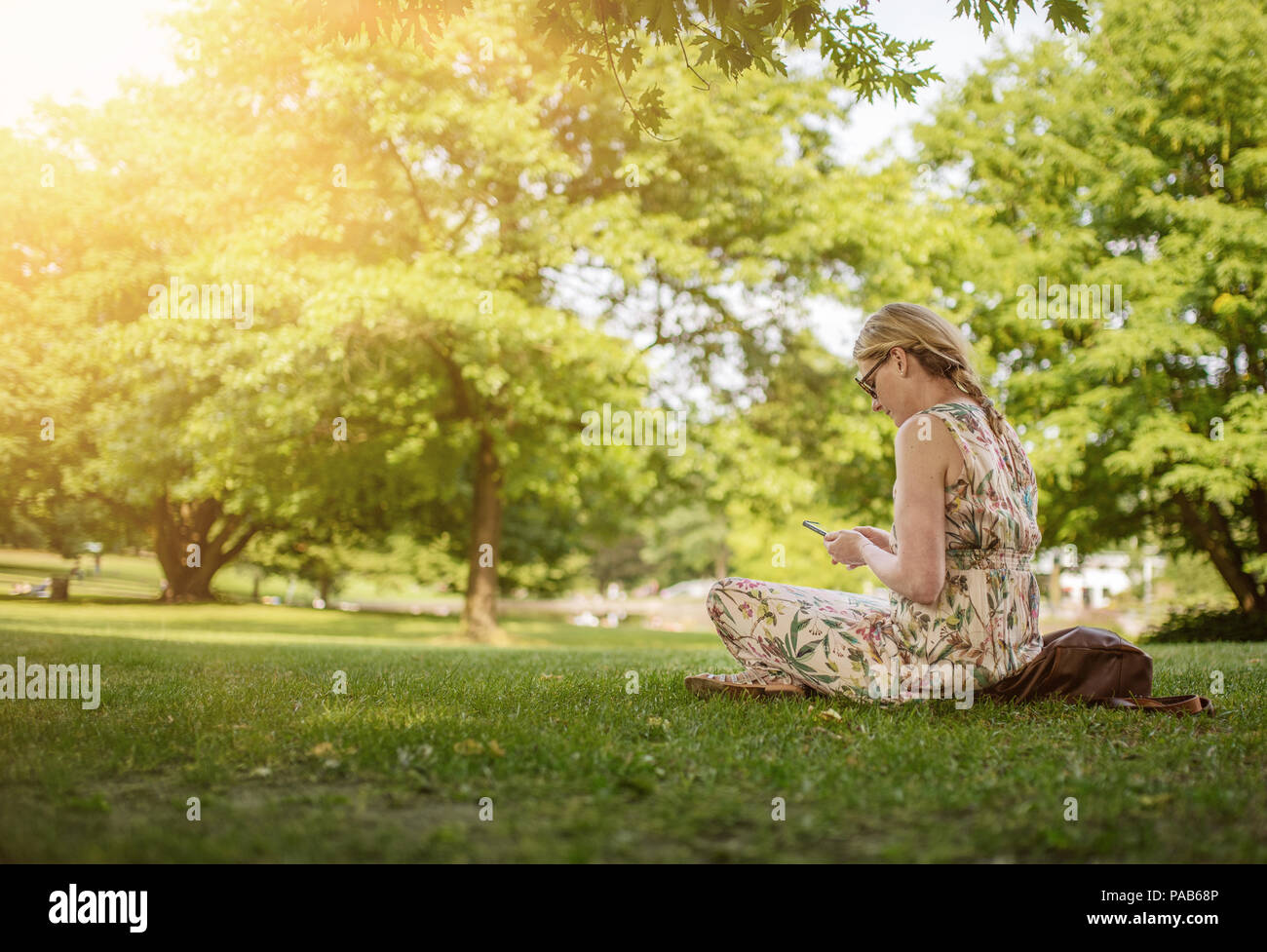 Donna che utilizza lo smartphone nel parco pubblico Foto Stock