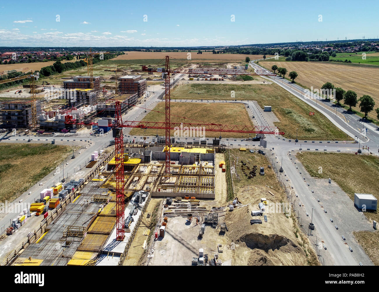 Sito in costruzione di gru e le conchiglie per case nuove, sullo sfondo la preparazione dell'area per il parcheggio di autovetture, foto aerea, realizzata con d Foto Stock