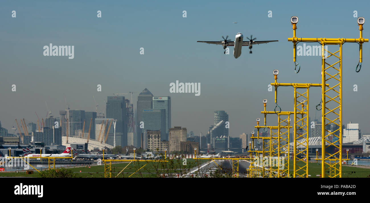 Piano a turboelica decollo dall'Aeroporto di London City con le torri di Canary Wharf e l'O2 in background Foto Stock