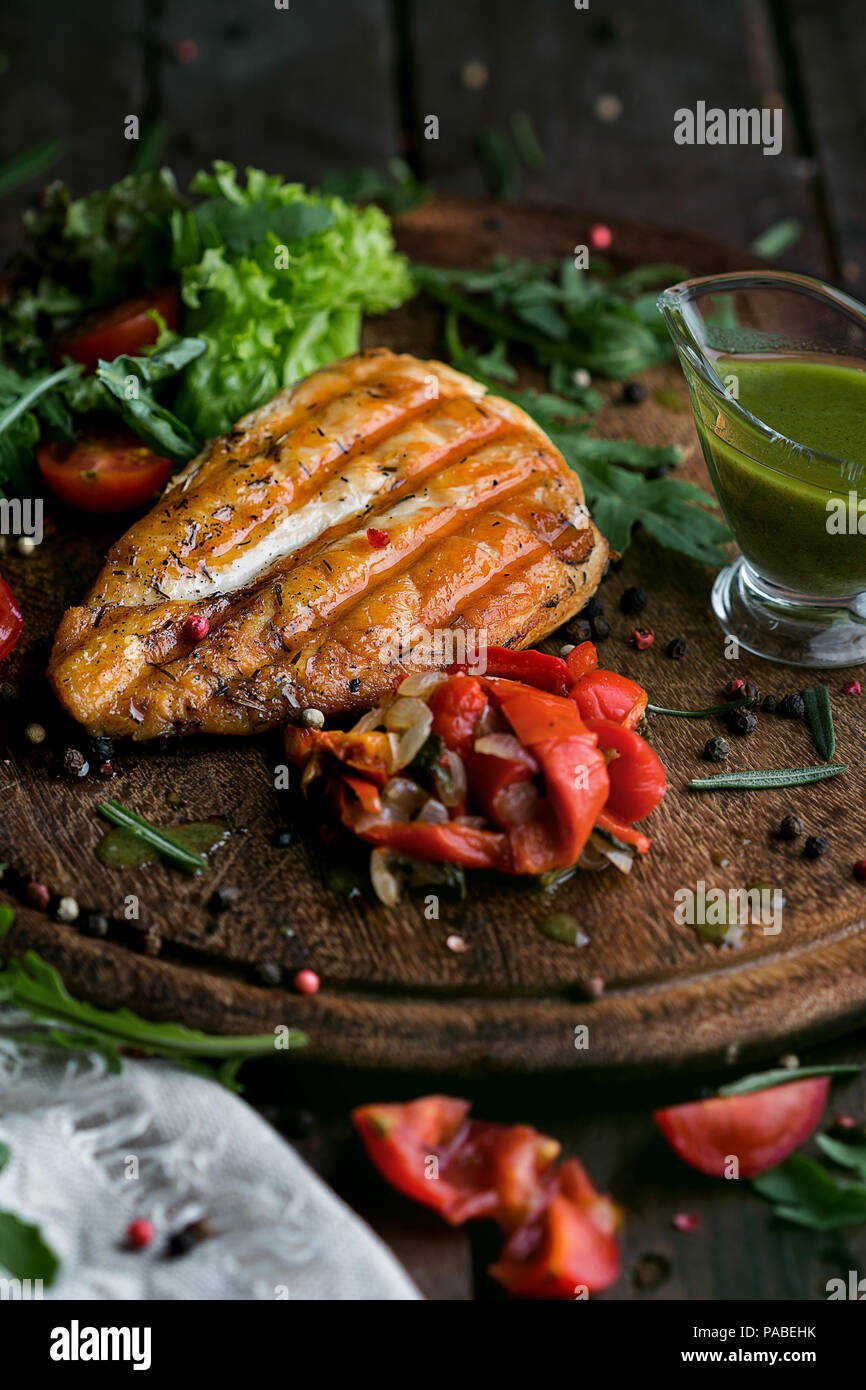 Gustosa e succosa bistecca di pollo su un piatto di legno. Foto Stock