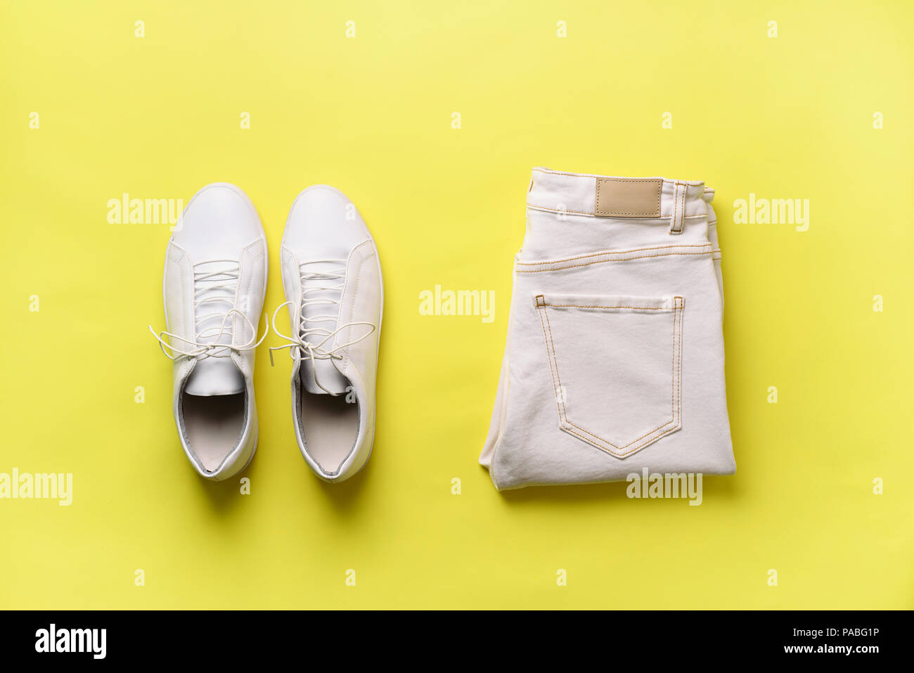 Femmina bianca sneakers e jeans su sfondo giallo con copia spazio. Vista dall'alto. Moda estate, shopping, capsule concetto guardaroba. Piatti creativi laici. Foto Stock